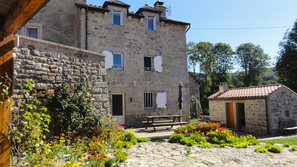 un bâtiment en pierre avec un banc devant lui dans l'établissement Gite les ducs, à Mialanes