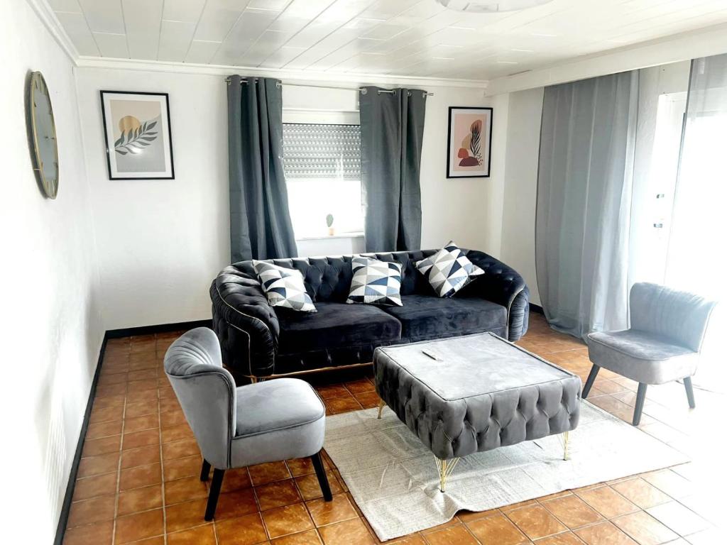 GadernheimにあるRELAX WOHNUNG LAUTERTALのリビングルーム(黒いソファ、椅子付)