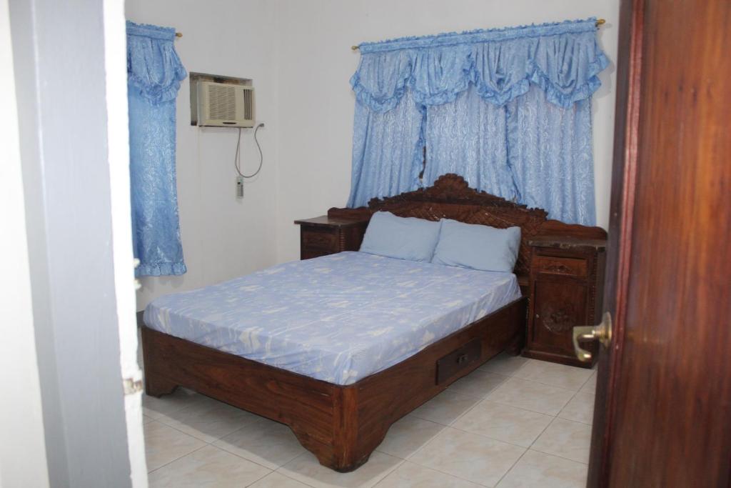Schlafzimmer mit einem Holzbett mit blauen Vorhängen in der Unterkunft Crossroads Beach House in Sablayan