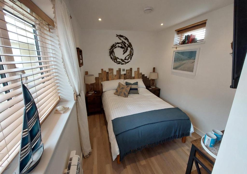 a small bedroom with a bed and a window at Beachcroft Beach Snug in Seaton