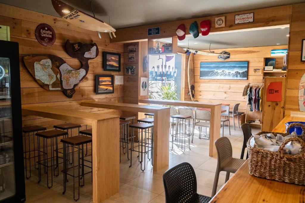 a bar in a restaurant with wooden walls and bar stools at Carving Surf Hostel in San Esteban de Pravia