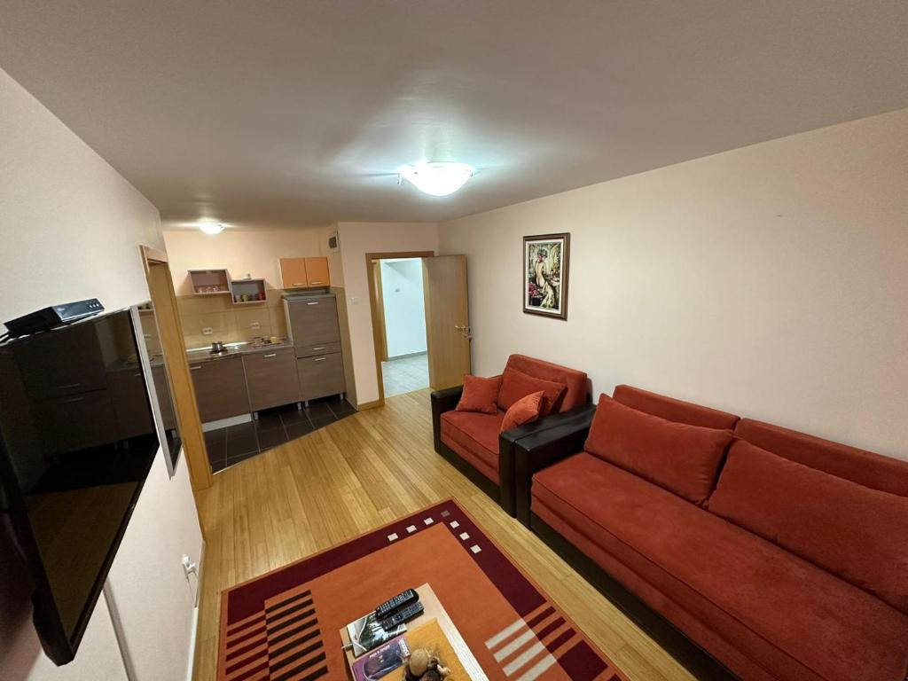 uma sala de estar com um sofá vermelho e uma cozinha em Apartmani Ušće em Trstenik
