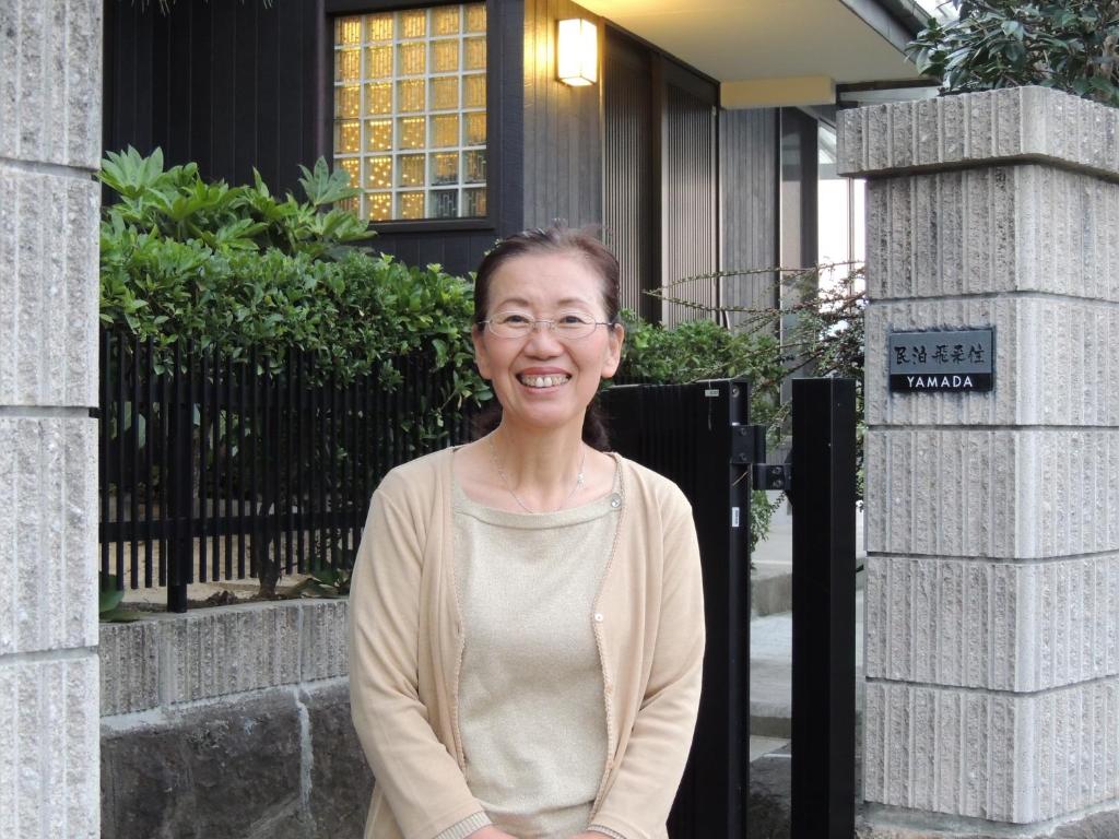 uma mulher em pé em frente a um edifício em Minpaku Hiraizumi em Hiraizumi