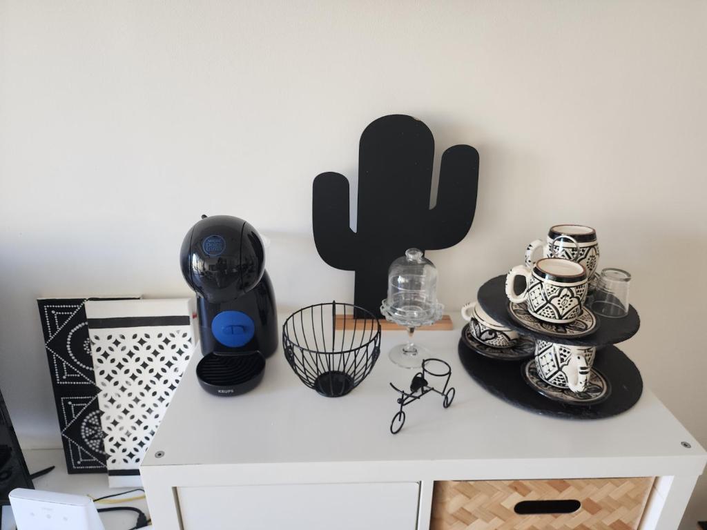a white cabinet with cups and glasses and a cactus at Chez Dju in Nouaceur