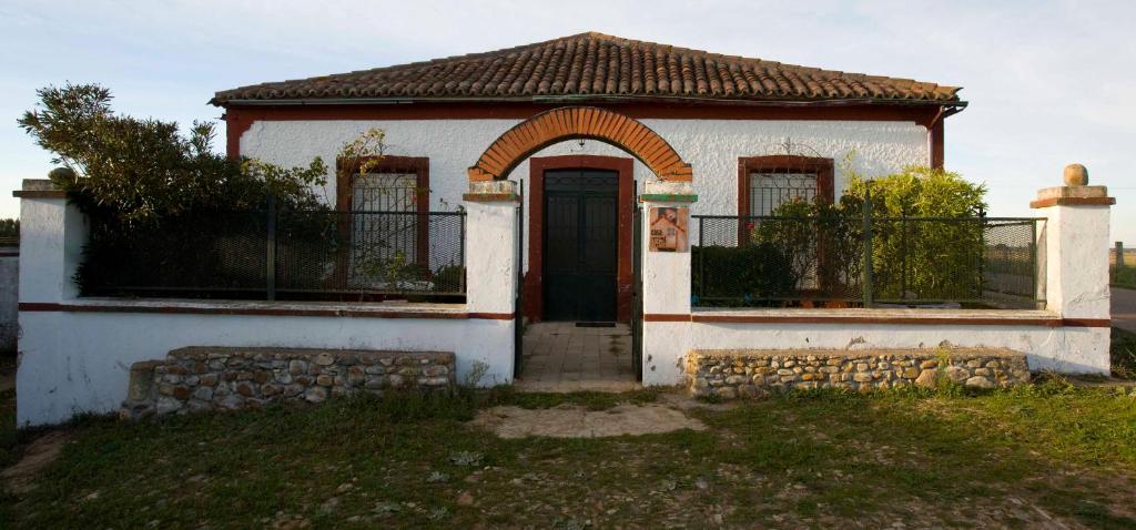 una pequeña casa blanca con una puerta en el césped en El Molino de Valeriano - Casa Rural, en Sancti-Spíritus