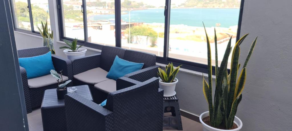 a room with chairs and potted plants and windows at Cazino Apartamento 4 in Praia