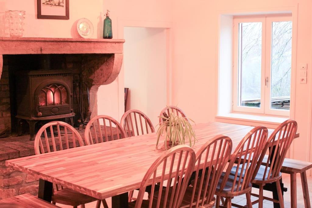 una mesa de madera y sillas en una habitación con chimenea en Pannonica charmante maison champêtre, en Montagny-sur-Grosne
