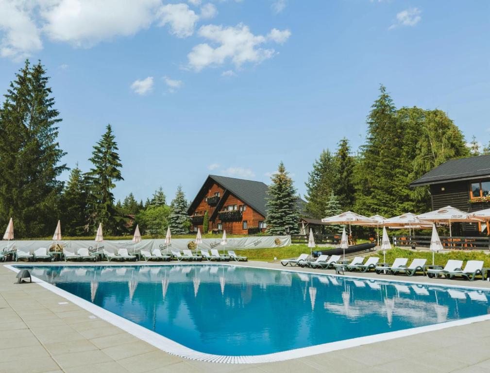 a large swimming pool with lounge chairs and a resort at Domeniul CRIS Vatra Dornei in Vatra Dornei