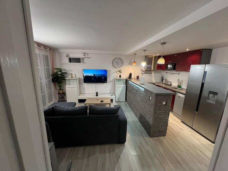 uma sala de estar com um sofá e uma cozinha com um frigorífico em Échappée mer LH em Le Havre