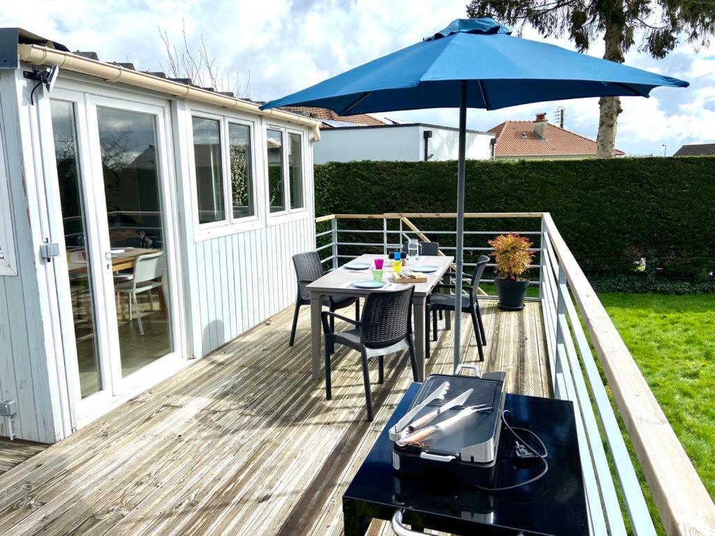 un patio avec une table et un parasol dans l'établissement Maison de plain pied proche Honfleur et Deauville, à Beuzeville