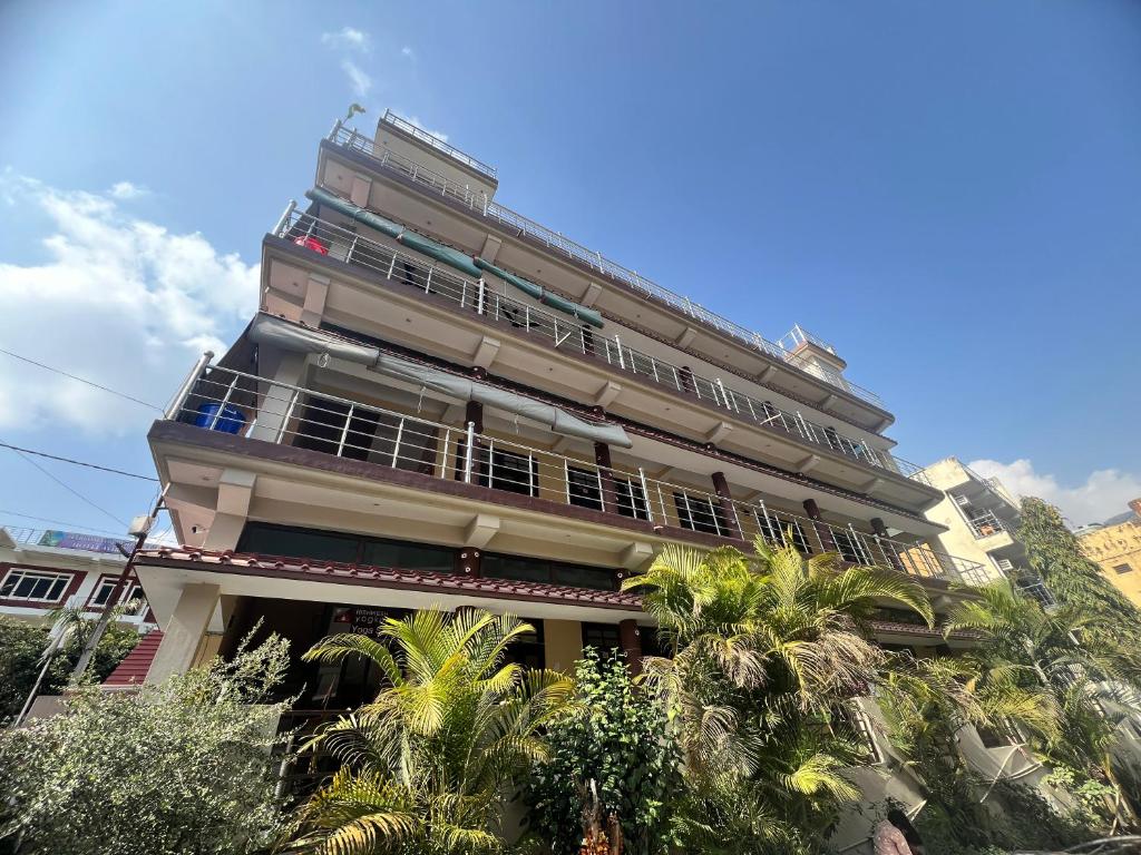 a tall building with palm trees in front of it at Tulsi Cottage in Rishīkesh