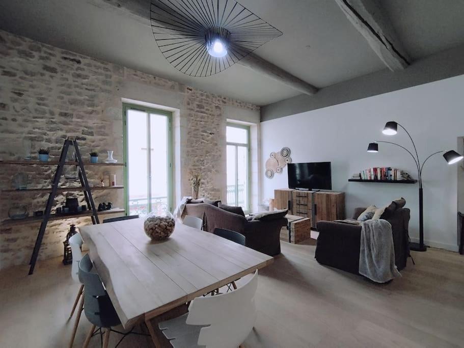 - un salon avec une table en bois et un mur en briques dans l'établissement Le Flavio à 2 pas des Arenes, à Nîmes