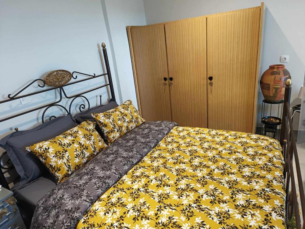 a bedroom with a bed with a yellow and black blanket at Polys Apartment and Paraskevi studio with view in Ptolemaida