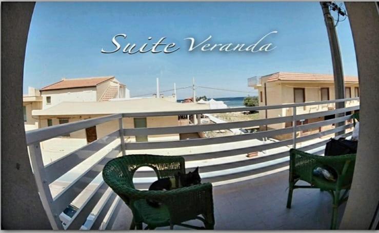 two green chairs sitting on a balcony near the beach at Casa Tramonto sull' Isola in Marzamemi
