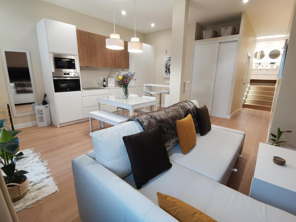 Apartamento de Lujo - A 10 minutos del centro في مدريد: غرفة معيشة مع أريكة بيضاء ومطبخ