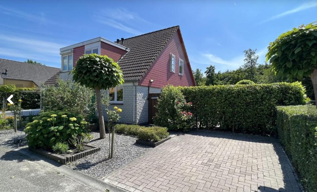 a house with a garden with a brick driveway at Vakantiehuis op Villapark Oesterbaai aan zee , met speeltuin grenzend aan de tuin in Wemeldinge