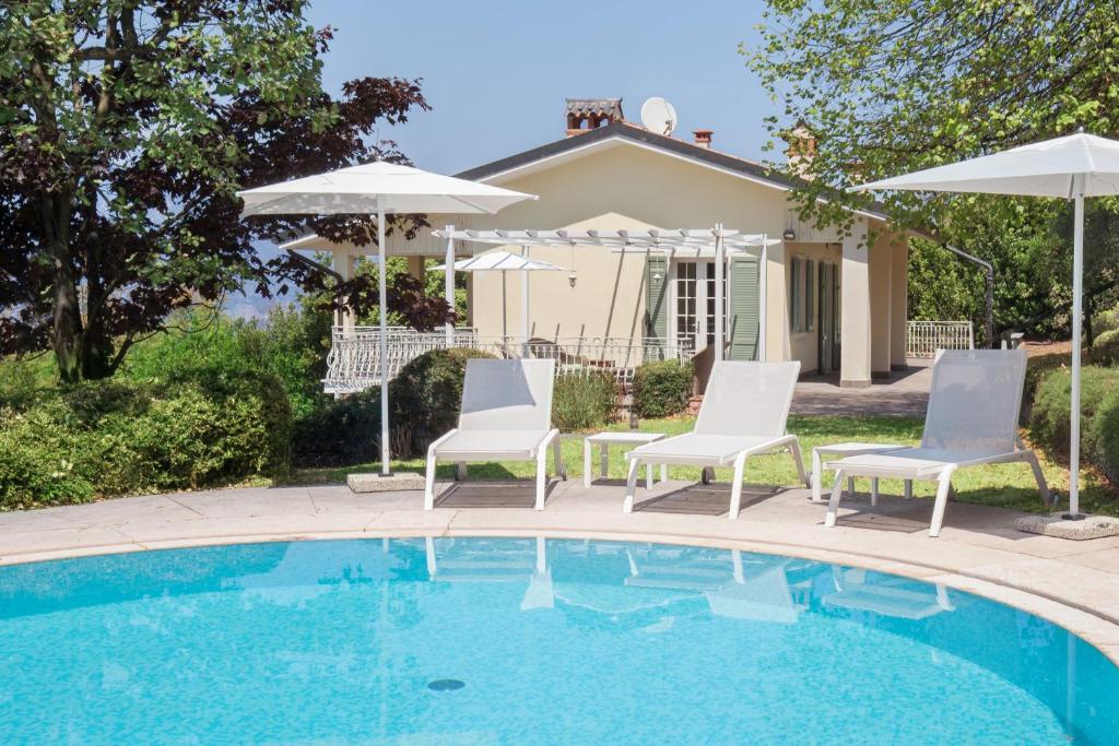 een zwembad met stoelen en parasols naast een huis bij Villa Ilaria with private pool and lake view in Torri del Benaco