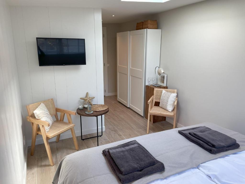 Un dormitorio con una cama y un televisor en la pared. en Villa de Duinfazant, en Bergen aan Zee
