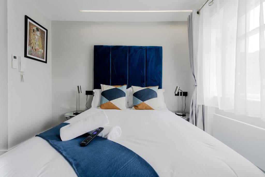 sypialnia z białym łóżkiem z niebieskimi akcentami w obiekcie London Central Studios w Londynie