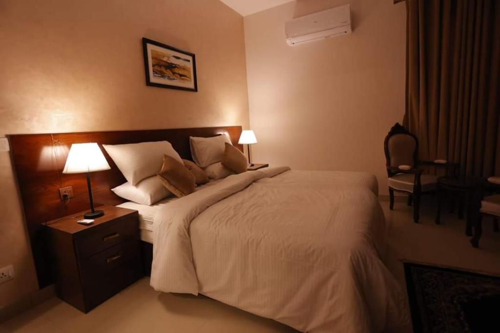 a bedroom with a bed with two lamps and a chair at Signature Boutique Hotel Karachi in Karachi