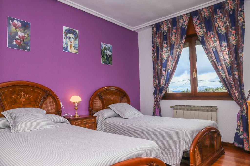 a purple bedroom with two beds and a window at Casa los Arcos in Trespaderne