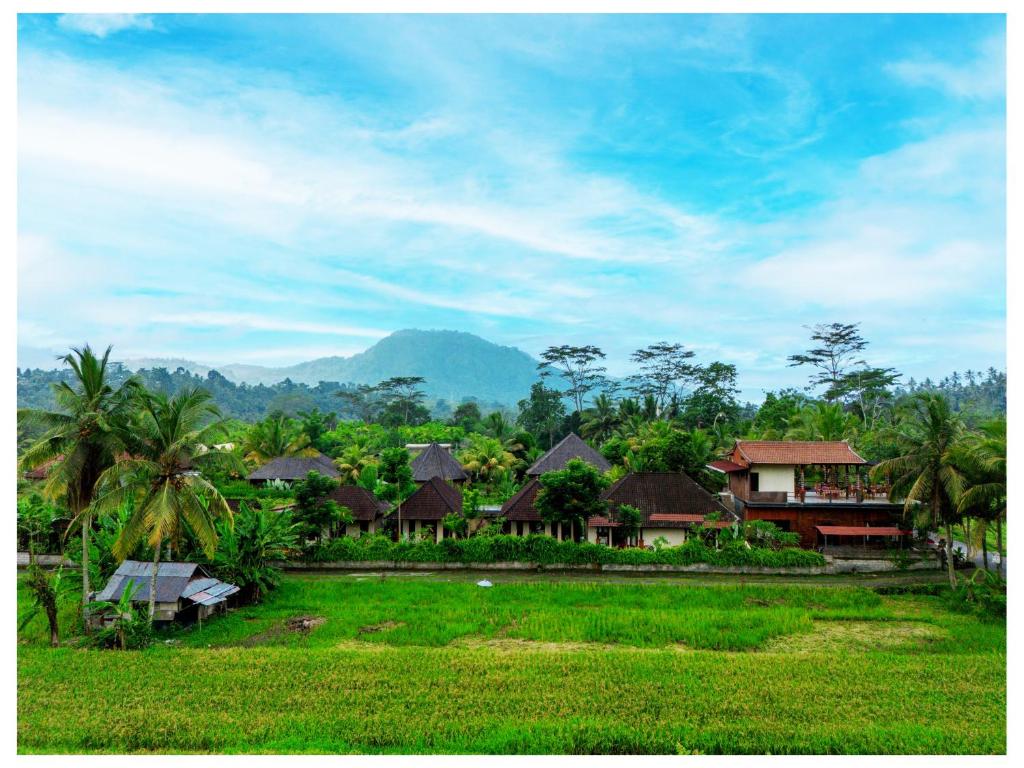 a village with houses and palm trees and a field at Gongwi Cottages Sidemen in Sidemen
