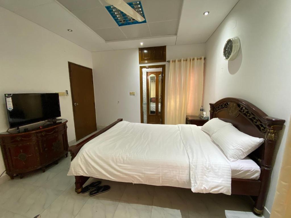 a bedroom with a white bed and a television at Gulshan Inn in Dhaka