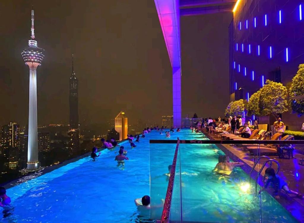 a pool with people in it at night with the space needle at The Platinum Kuala Lumpur By Newcastle in Kuala Lumpur