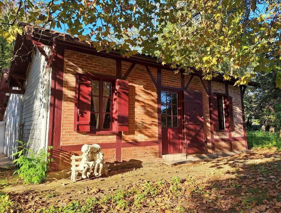 un chien assis devant une petite maison dans l'établissement POASANA, à Saint-Julien-en-Born