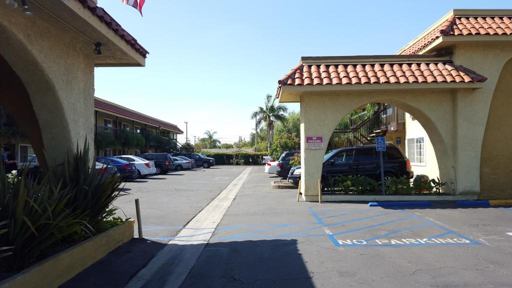 un parking avec des voitures garées à côté d'un bâtiment dans l'établissement Anaheim Astoria Inn & Suites, à Anaheim