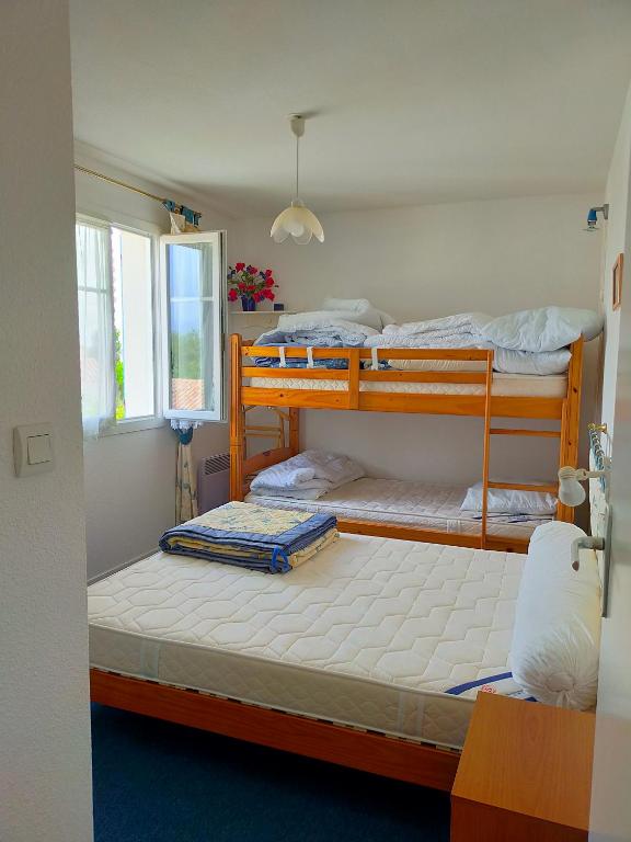 two bunk beds in a room with a window at Grand T3 bien équipé , standing , calme in Vaux-sur-Mer