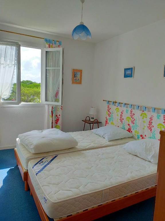 two beds in a bedroom with a window at Grand T3 bien équipé , standing , calme in Vaux-sur-Mer