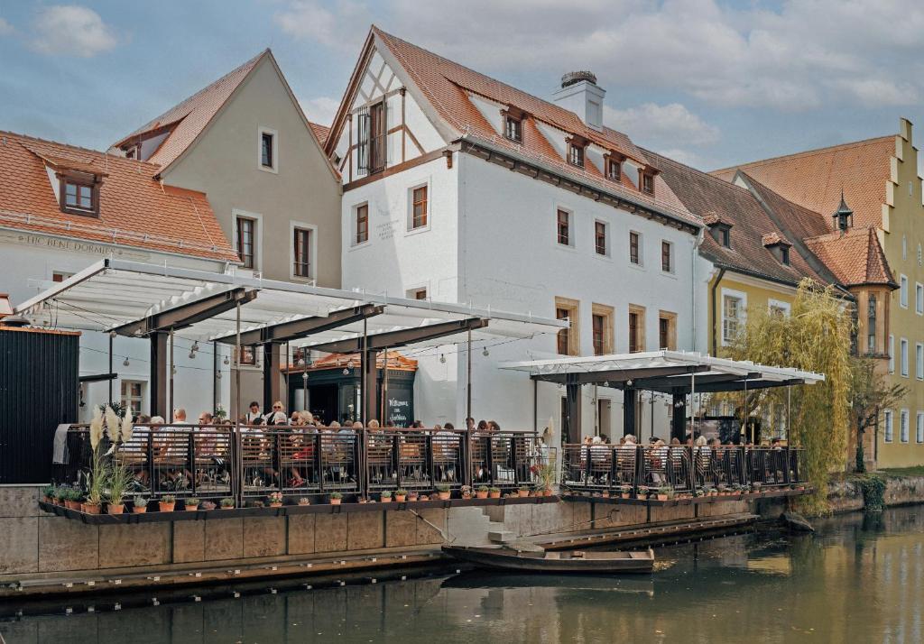 a restaurant on a bridge next to a river at Bootshaus Amberg in Amberg