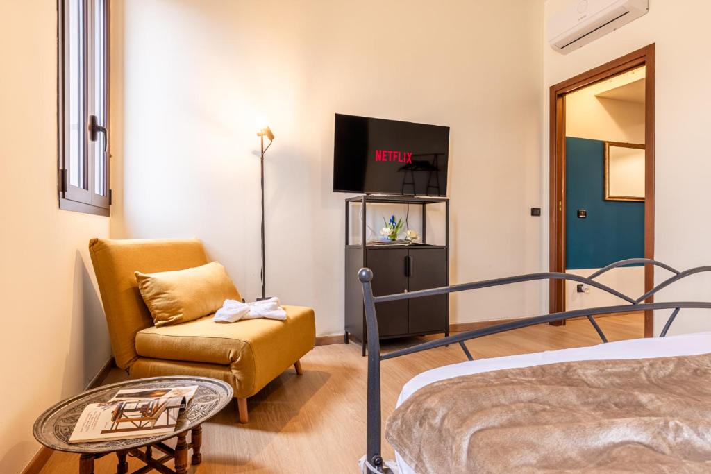 a bedroom with a bed and a chair and a tv at Certosa Charme 10 Minuti da SAN SIRO e RHO FIERA in Milan