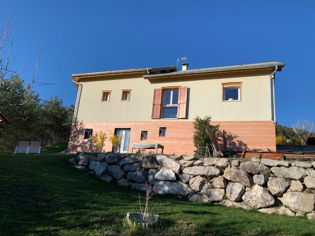 a house with a stone wall in front of it at T2 au calme montagne et lac in La Bâtie-Vieille