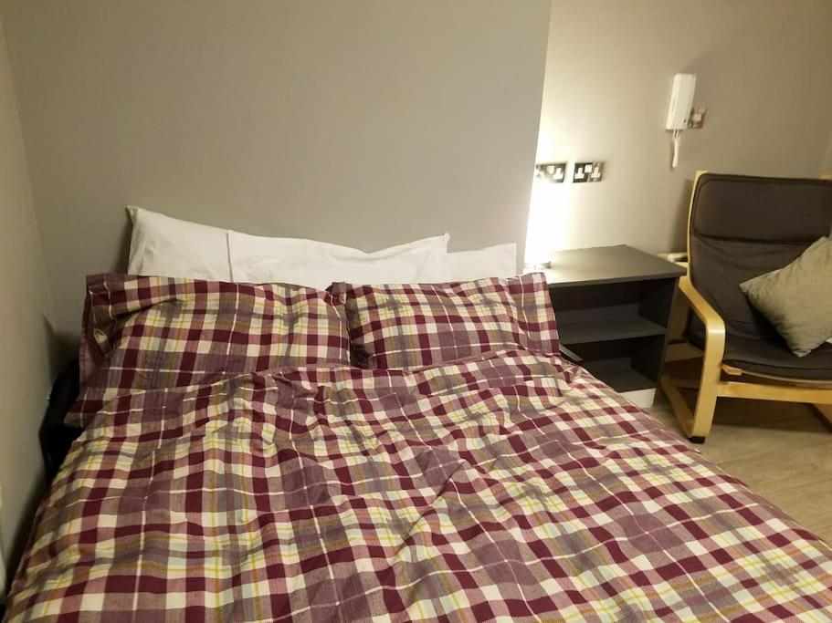 ein Bett mit einer karierten Decke darüber in der Unterkunft Heart of City DE1 Studio Apartment in Derby