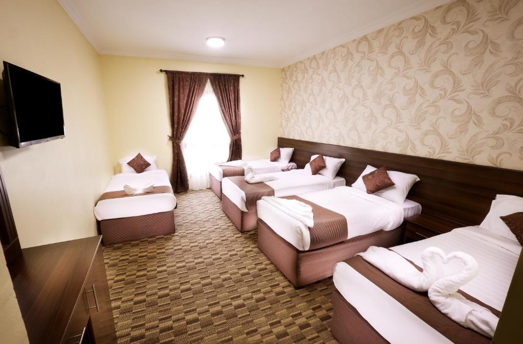 a hotel room with four beds and a television at مرجان أنوار الروضة in Makkah