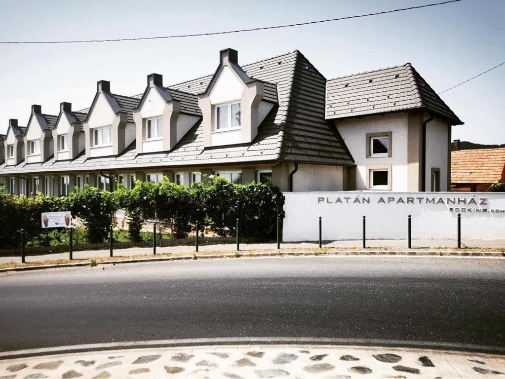 a building with a sign on the side of a street at Platán Apartmanház in Balatongyörök