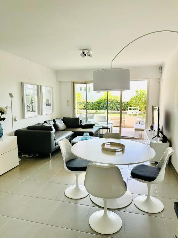 un salon avec une table et des chaises blanches dans l'établissement Résidence PARADIS BLEU - Appt 3P, à Cannes