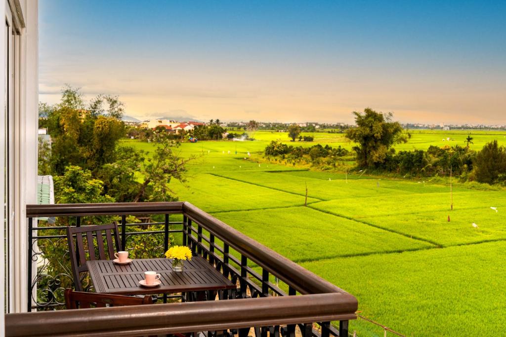 balcón con mesa y vistas a un campo verde en Iris De Villa Hoi An en Hoi An