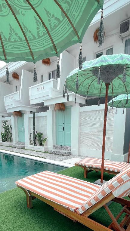 - une piscine avec 2 chaises longues et un parasol dans l'établissement Kaktus Boutique Apartments Bali - ADULTS RETREAT, à Legian