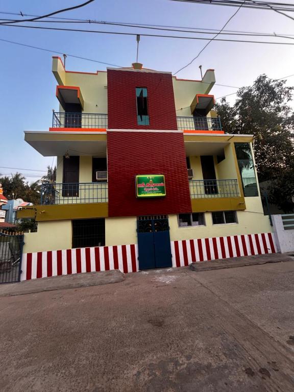 a red and white building with a fence in front of it at Sri Thirumal Home Stay in Kumbakonam