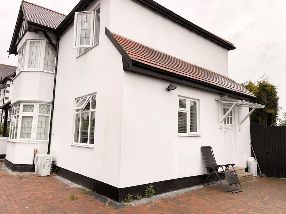 a white house with a chair in front of it at Nice and Cosy Studio Flat in Carshalton