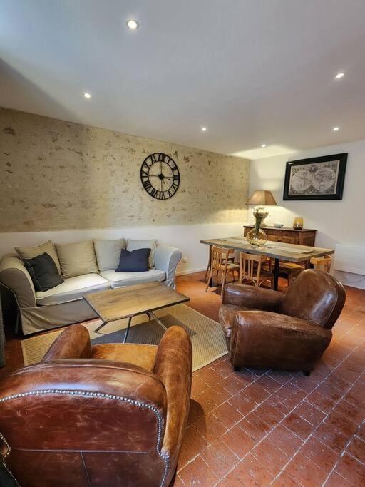 - un salon avec des meubles en cuir et une horloge murale dans l'établissement Le Nid'Ainay Maison de Village entièrement rénovée, à Ainay-le-Vieil
