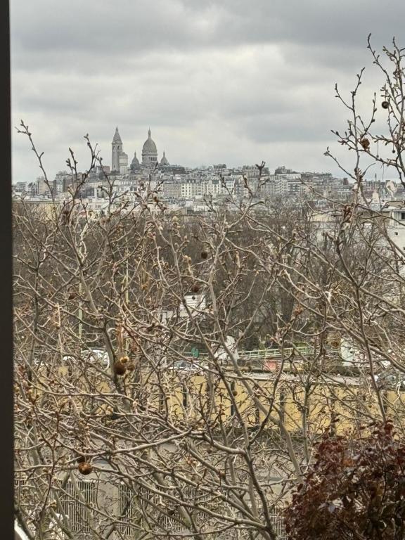 a view of the city from behind a tree at Appartement Luxueux 3 pièces climatisé avec Terrasse, 5 couchages - 17ème Arrondissement de Paris in Clichy
