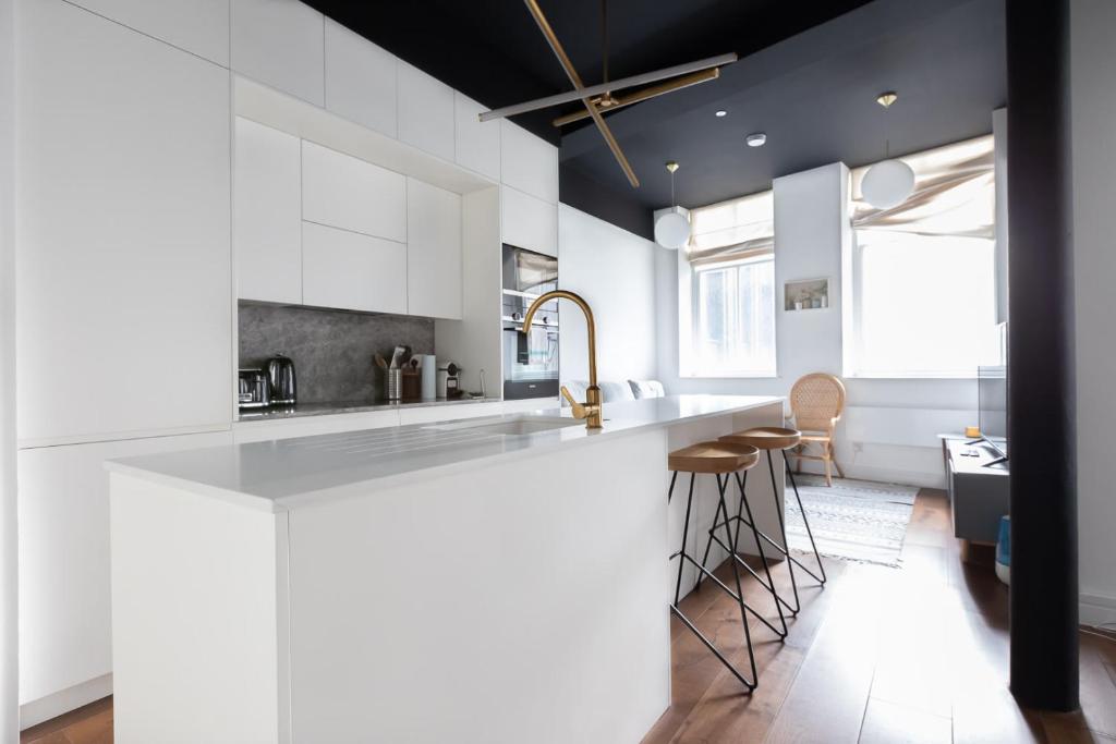 a kitchen with white cabinets and a counter with stools at Lovely 1 Bedroom Apartment Holborn London in London