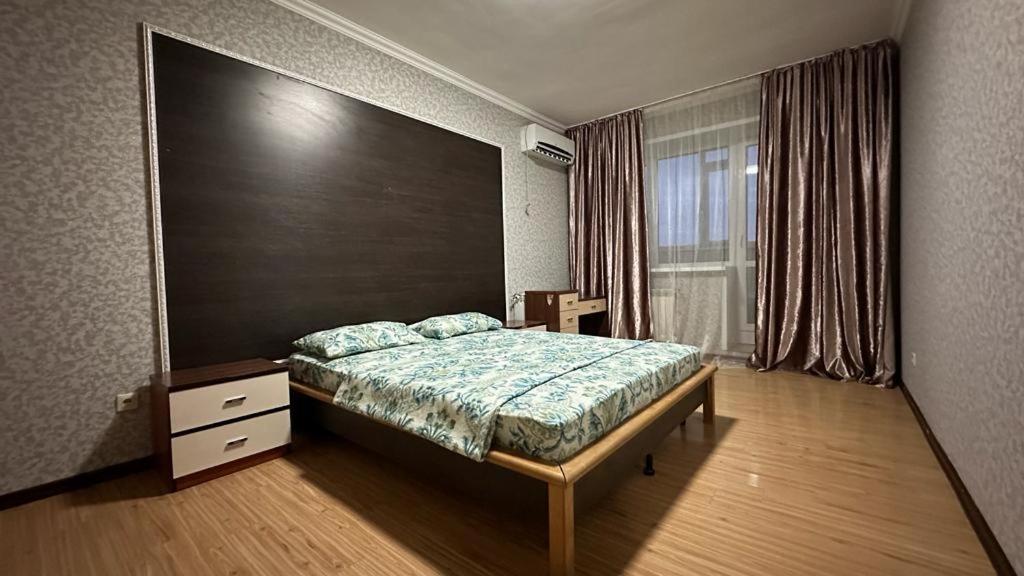 ein Schlafzimmer mit einem Bett und einem großen Fenster in der Unterkunft Кунжут in Aqtöbe