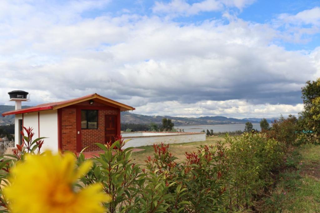 a small house in a field with a lake at Alojamiento Villa Doralis in Guatavita