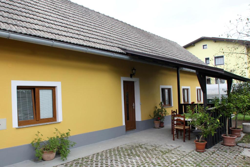 Kmečka hiša Rodica في دومزالي: منزل أصفر مع شرفة مع طاولة وكراسي