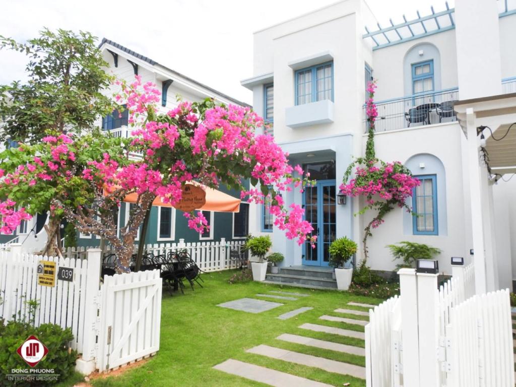 einen weißen Zaun vor einem Haus mit rosa Blumen in der Unterkunft Novaworld Phan Thiết - Đông Phương Villa in Bình Tú